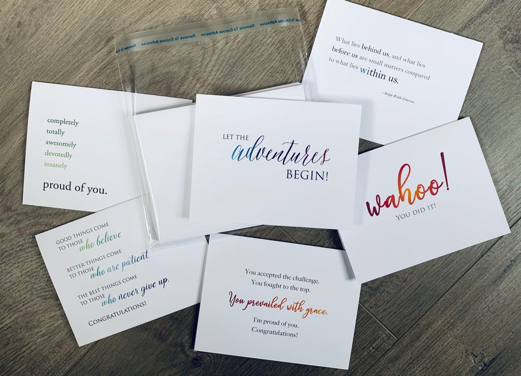 Six white congratulations cards are overlapped on a wooden background. Each card has a motivating and congratulatory sentiment in a mix of fonts and colors. Congrats collection by Stationare.