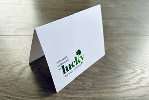 A folded white notecard says "so honored. so fortunate. so lucky that you're my firend." with a small green shamrock. Friendship Luck collection by Stationare.