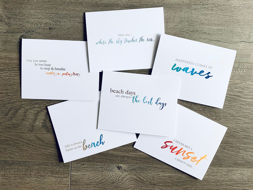 A collage of white notecards are overlapping on a gray wood background. Each card has a colorful saying related to the beach. Beach Life collection by Stationare.