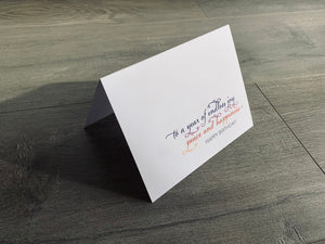 A white card is propped on a gray wood floor. The card reads, "to a year of endless joy, peace and happiness! Happy Birthday!" birthday card by Stationare