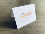 A white folded notecard is propped up on a wooden floor. The card says, "hey there pumpkin." From the I Love Fall Collection by Stationare.