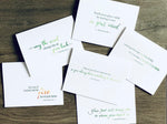 Six white notecards are overlapping one another on a wooden background. In mostly green text, each has an inspirational Irish proverb. Irish Inspirations collection by Stationare.