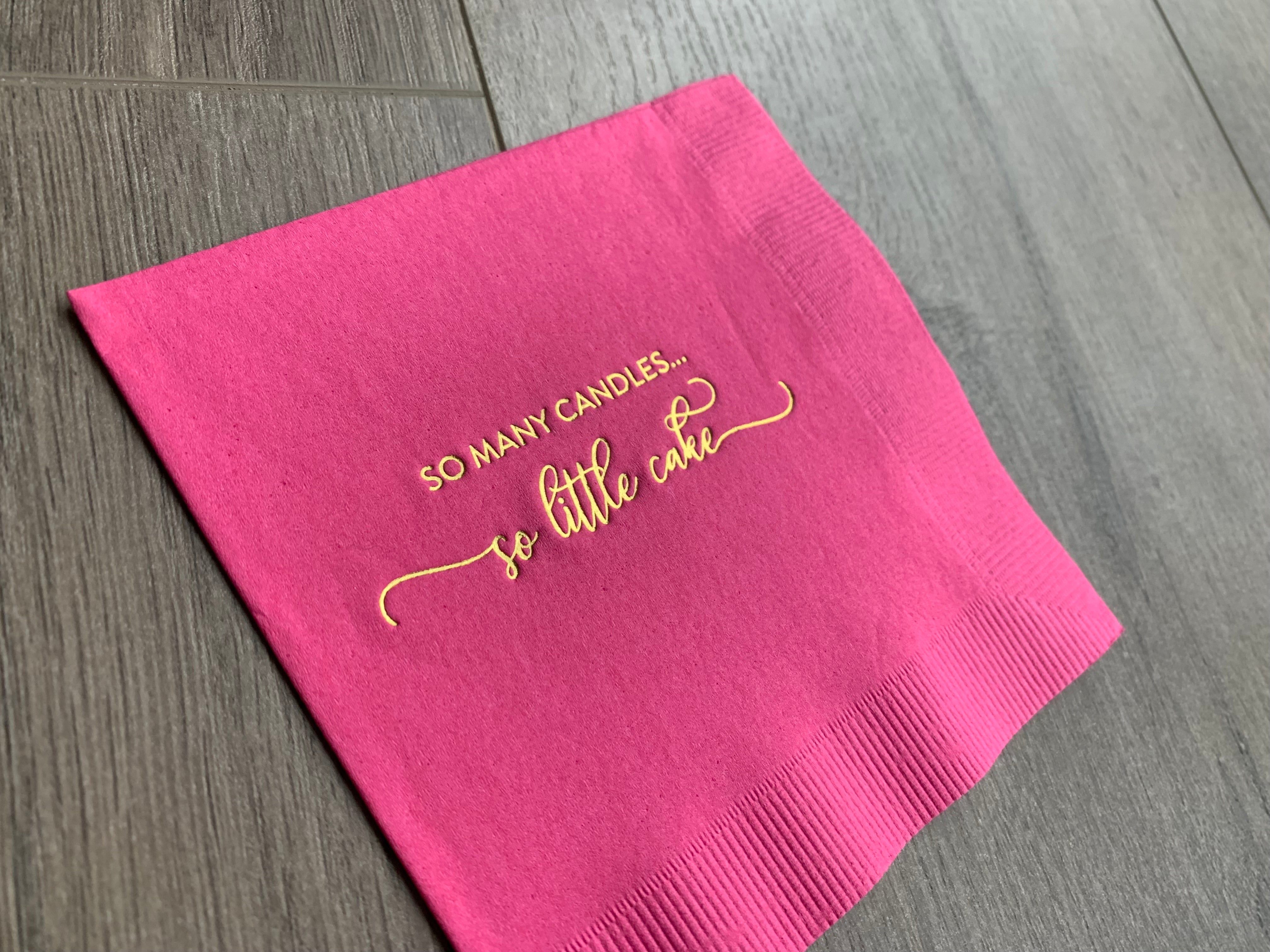closeup image of the metallic gold foil printing that reads "so many candles... so little cake" on a bright hot pink cocktail napkin by Stationare