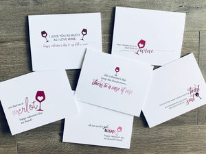 A collage of six white notecards lie on a gray wooden background. Each card has a wine-themed saying in regard to friendship and love. The Valen-Wine collection by Stationare.