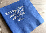 A royal blue napkin lies angled on a wooden backdrop. In reads, "here's to things we'll never remember with friends we'll never forget! cheers!" in a script silver foil.