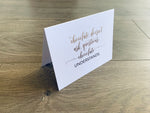 White folded notecard propped up on a wooden background. In script font, it reads "Chocolate doesn't ask questions. Chocolate understands." Card by Stationare.