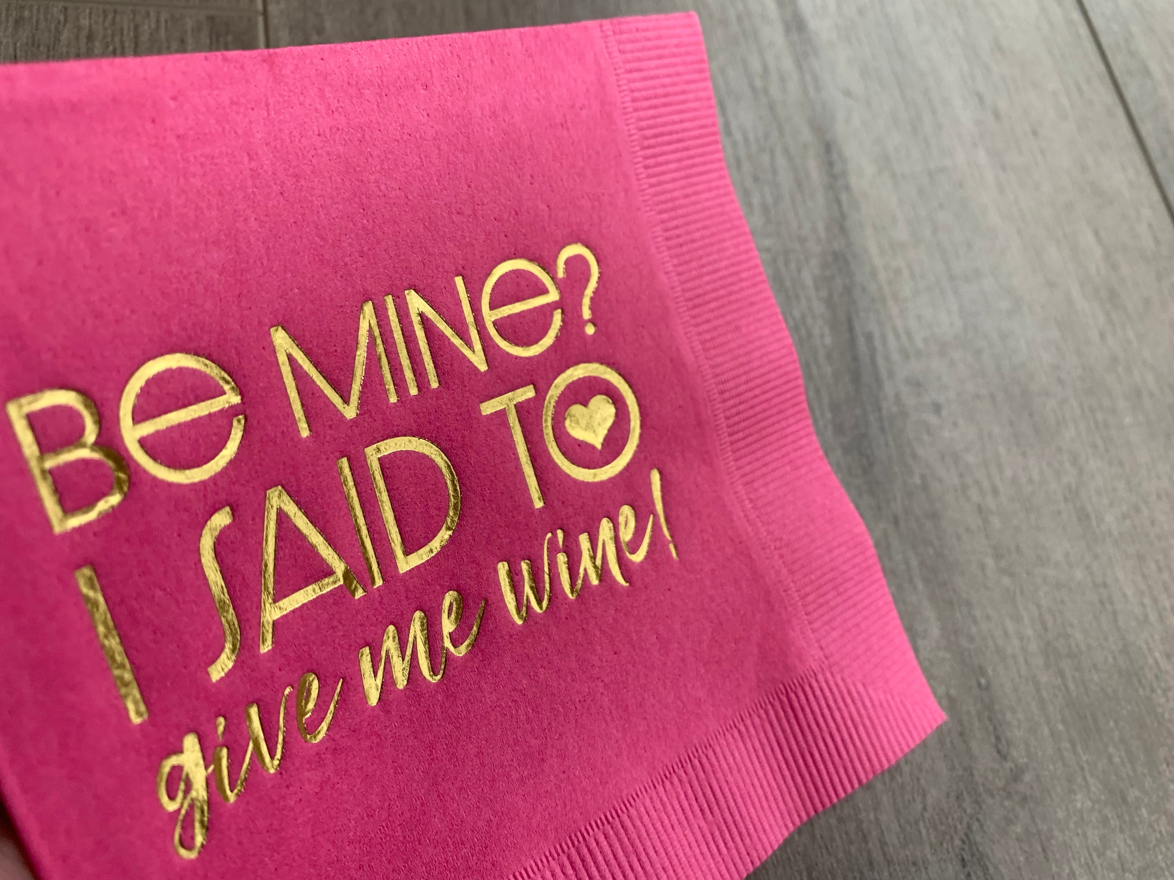 closeup image of gold foil printing on hot magenta pink cocktail napkin. Gold foil printing reads Be Mine? I said to give me wine! Funny cocktail napkin for valentine's day with your significant other or best girl friends!