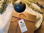 image of eat drink and be merry hanging gift tag on box under christmas tree by stationare