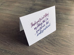 White folded notecard propped up on a wooden floor. In purple script font, it reads, "Thank you for not telling my siblings that I'm your favorite. That would get awkward." Mother's Day card by stationare