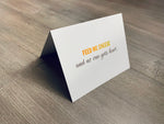 A white notecard is on a gray wooden floor. The card says, "Feed me cheese and no one gets hurt." Cheese Lovers collection by Stationare.