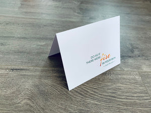A white folded notecard sits on a gray wood floor. It reads, "Do as if there were fire in your skin." Irish Inspirations collection by Stationare.