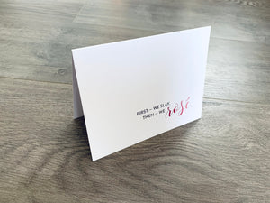 A folded white notecard from Stationare's Wine and Champagne Lovers Collection stands on a wooden floor. In pink and gray printing, it says, "first, we slay. Then we rose."