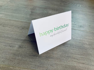 A white card is propped on a gray wood floor. The card reads, "Happy birthday my beautiful friend!" Birthday Card by Stationare
