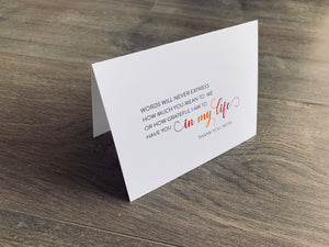A white folded notecard is propped up on a wooden floor. On the card, it says, "Words will never express how much you mean to me or how grateful I am to have you in my life. Thank you, Mom." Mother's Day card by Stationare