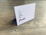 A white, folded notecard sits on a wooden floor. The card says, "Live. Express. Dream. Envision. Style. Create." Creativity collection by Stationare.