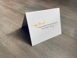 A white notecard is on a gray wooden floor. The card says, "my friend... we go together like wine and cheese. I'm so lucky to have you." Cheese Lovers collection by Stationare.