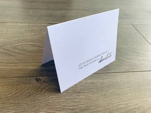 A white, folded notecard is propped up on a wooden background. The card reads "Let  us never underestimate the true power of chocolate." Stationare's Chocolate Lovers notecard collection.