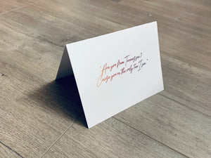 A folded white notecard is propped up on a wooden floor. The card reads, "Are you from Tennessee? 'Cause you're the only ten I see." Stationare's Pick Up Lines collection.