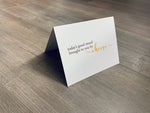 A white notecard is on a gray wooden floor. The card says, "today's good mood brought to you by cheese." Cheese Lovers collection by Stationare.